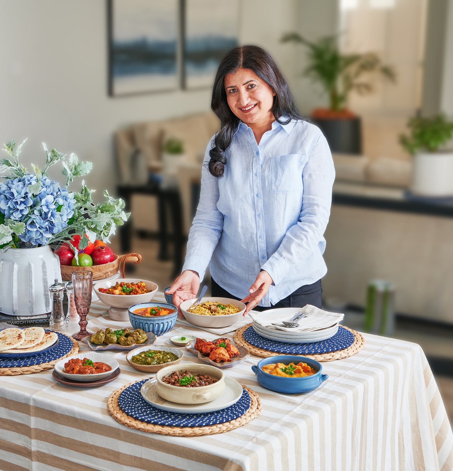Sona at her table, presenting a spread of freshly cooked Indian dishes
